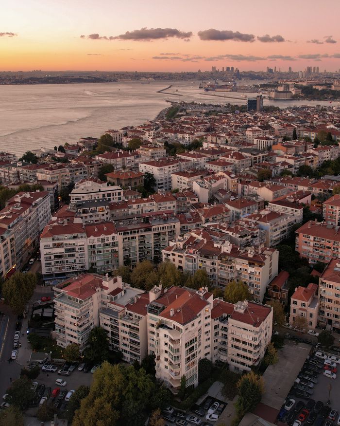 Aerial shot of Istanbul's coastal cityscape at sunset, showcasing urban architecture and the serene sea.