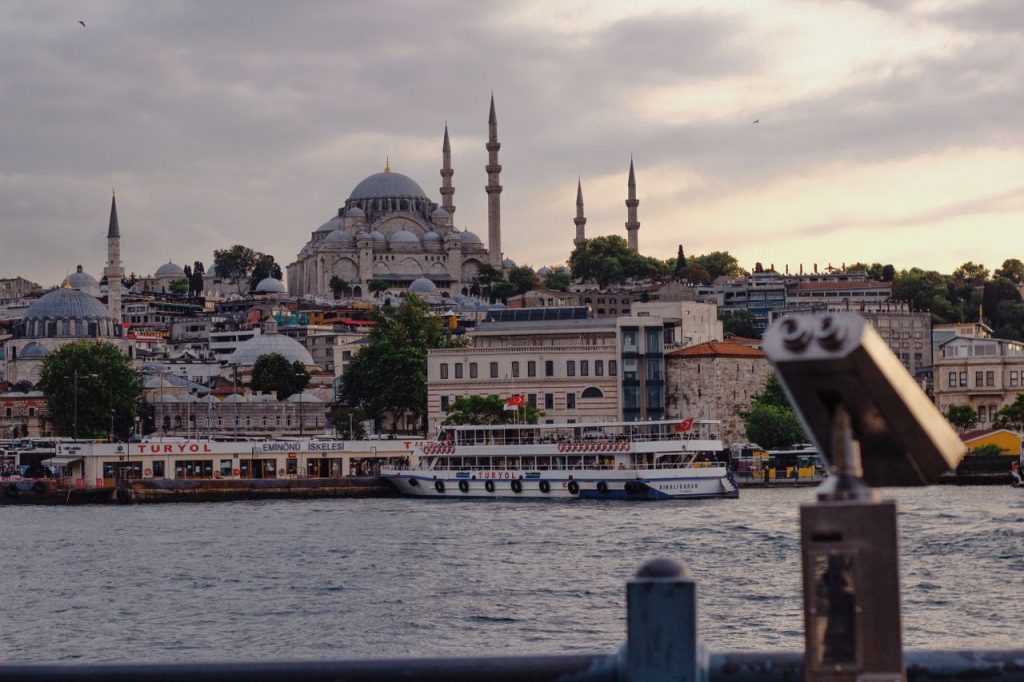 Beautiful view of the Istanbul skyline with Suleymaniye Mosque at dusk, featuring a tour boat on the Bosphorus Strait.